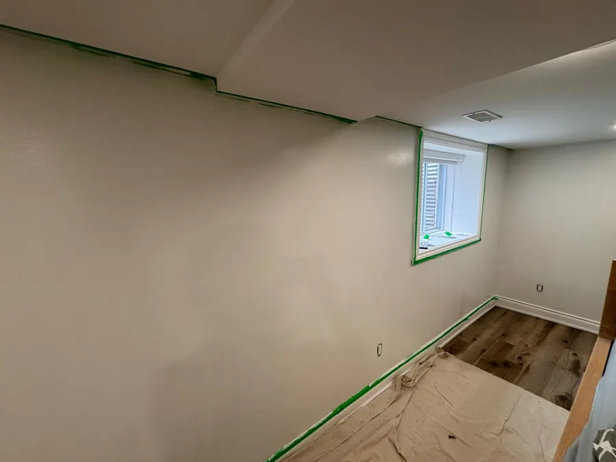 Freshly painted basement room with wall repairs completed and edges taped